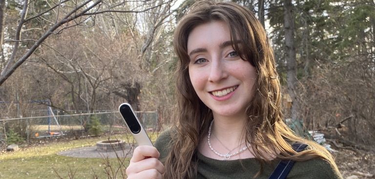 Young female holding her Roger On microphone and smiling - an outdoor scene.