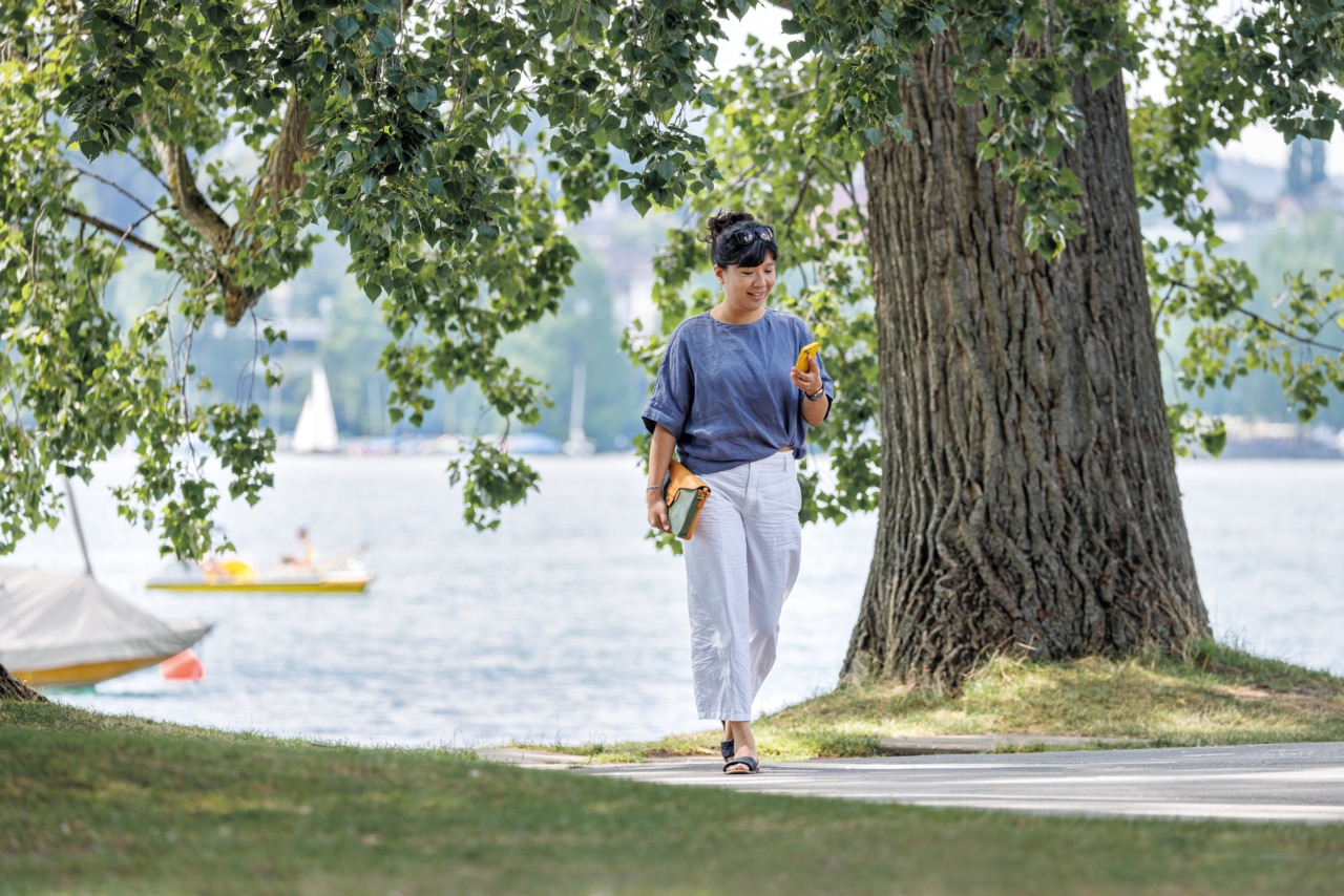 Woman adjusting phone while walking