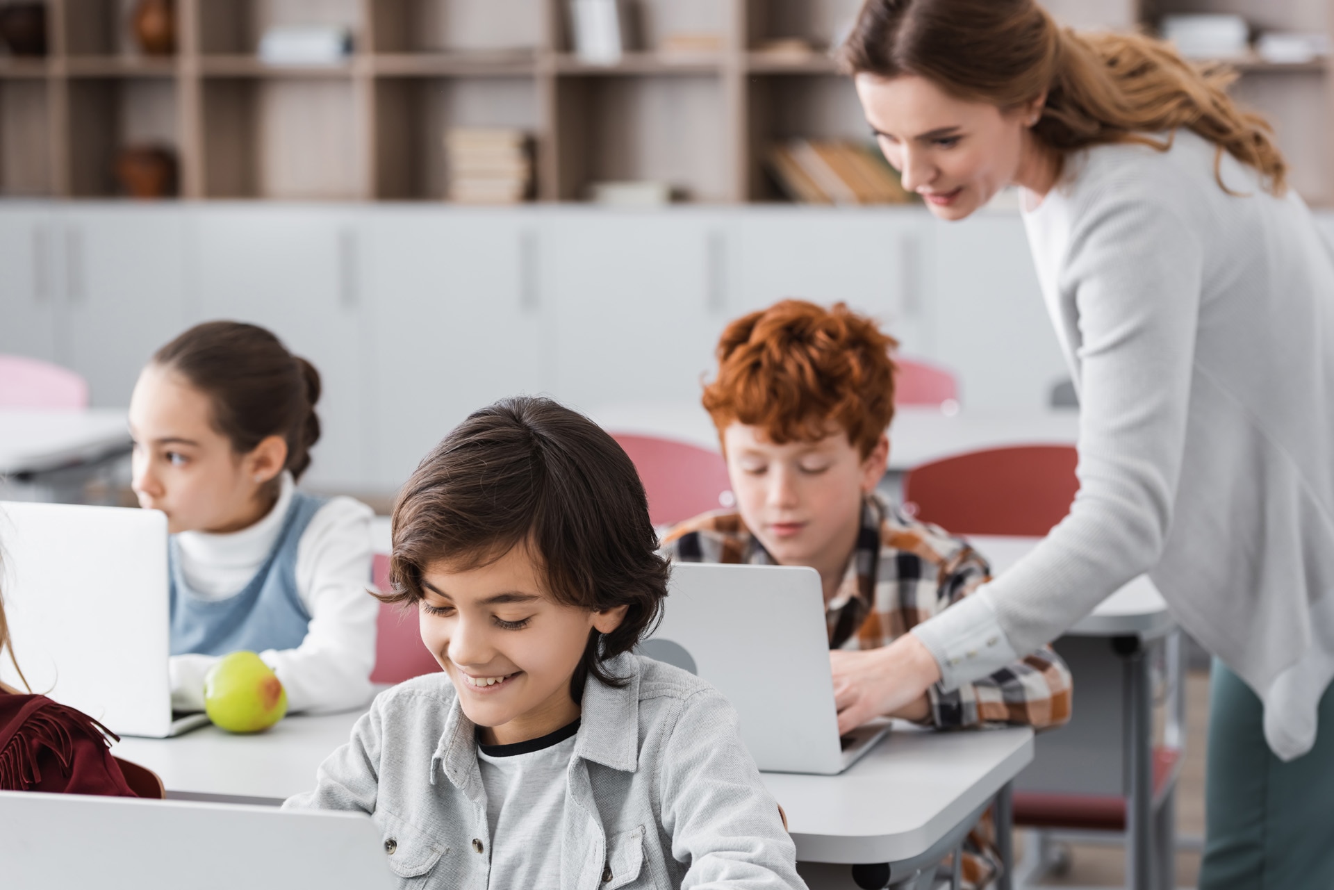 Female teacher and three pupils in a classroom.