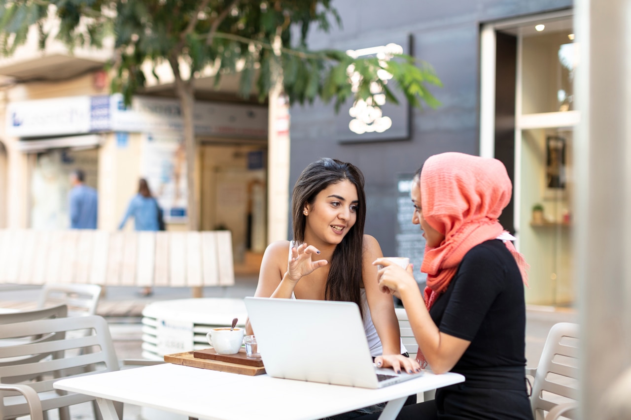 Two friends sitting at outdoor table and having a conversation together